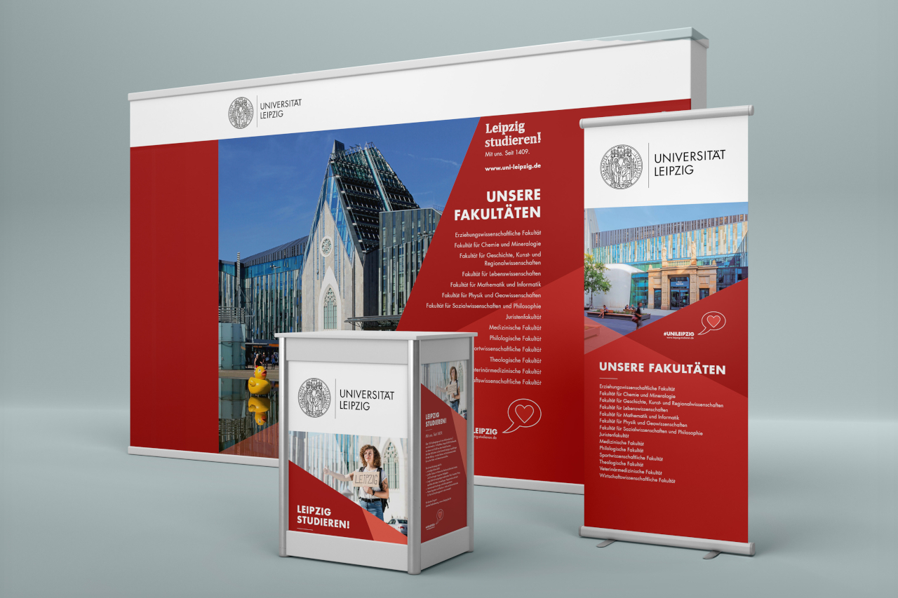 Messestand der Universität Leipzig in Rot, Grau und Weiß mit einheitlich gestaltetem Roll-Up, Messewand, Pult und Wort-Bildmarke.